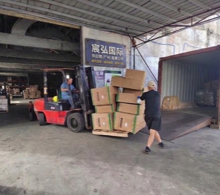 堆高機與人員將棧板紙箱裝入貨櫃，背景為宸弘國際供應鏈廣州倉庫